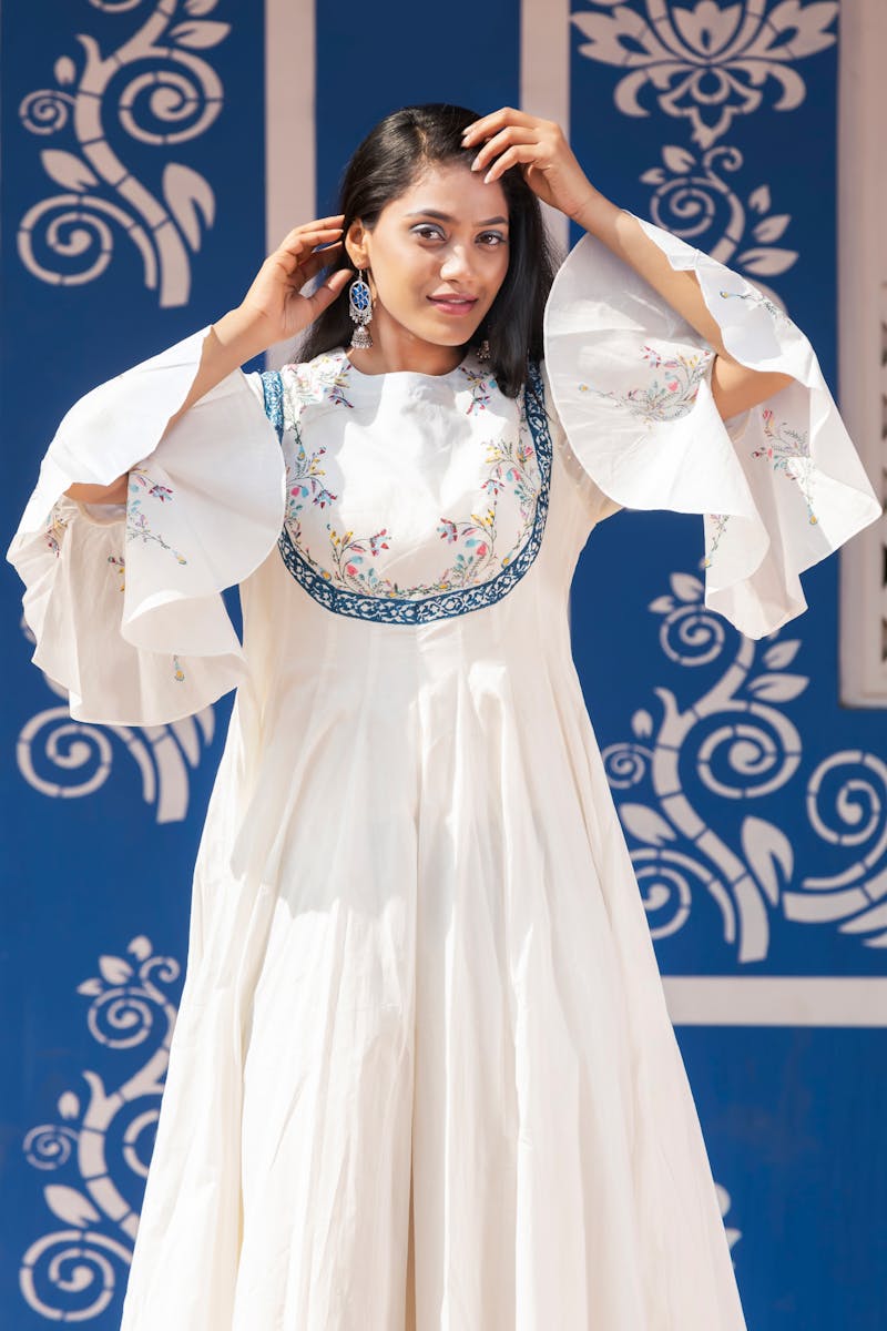 Young woman posing in an elegant embroidered dress against a traditional Jaipur backdrop.