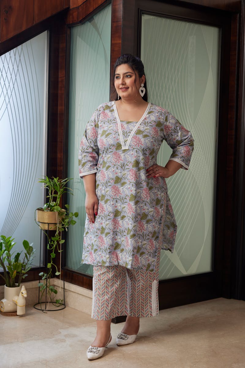 Portrait of a confident woman in a floral kurta standing indoors with plants.